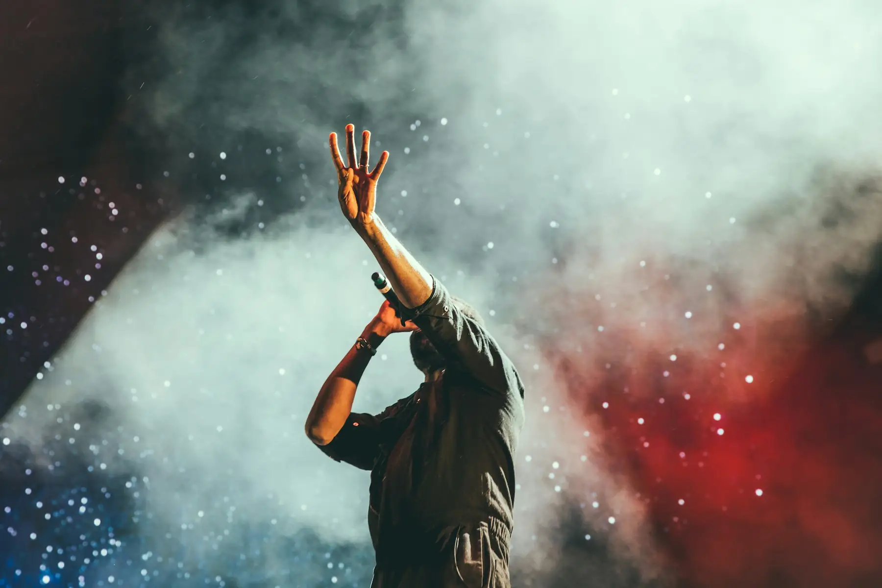 A performer singing into warm stage light.